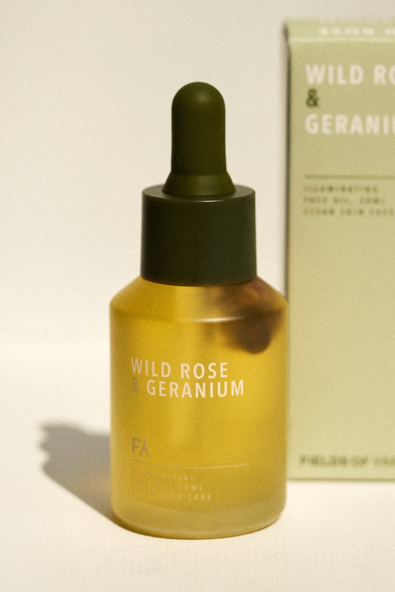 Stil life picture of the Wild Rose & Geranium Illuminating Face Oil by Fields of Yarrow with its packaging