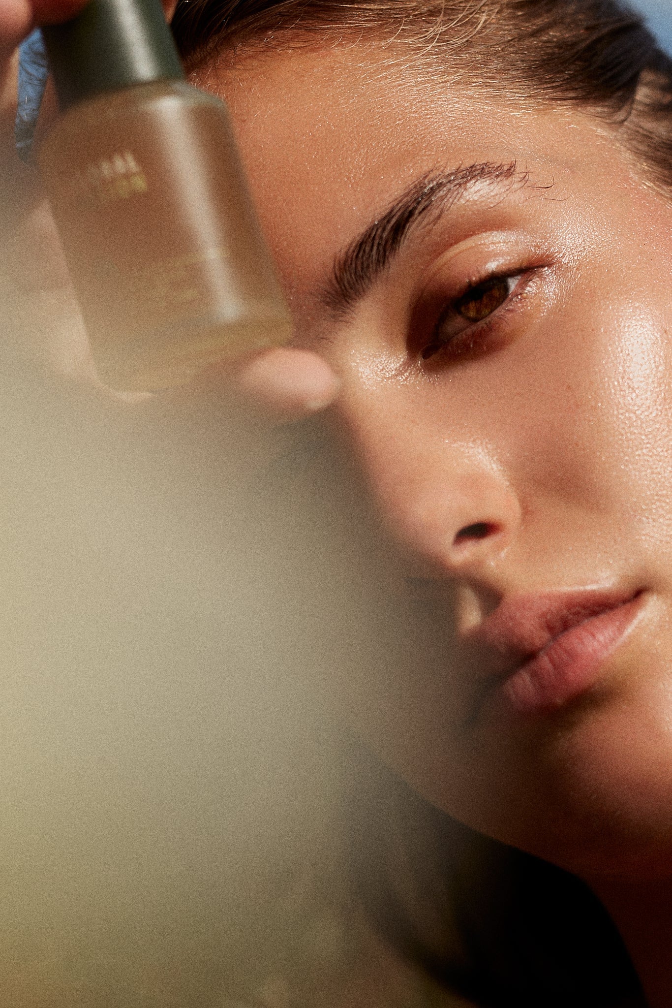 Picture of a model holding the Floral Fusion Radiance Daily Serum by Fields of Yarrow next to ther face